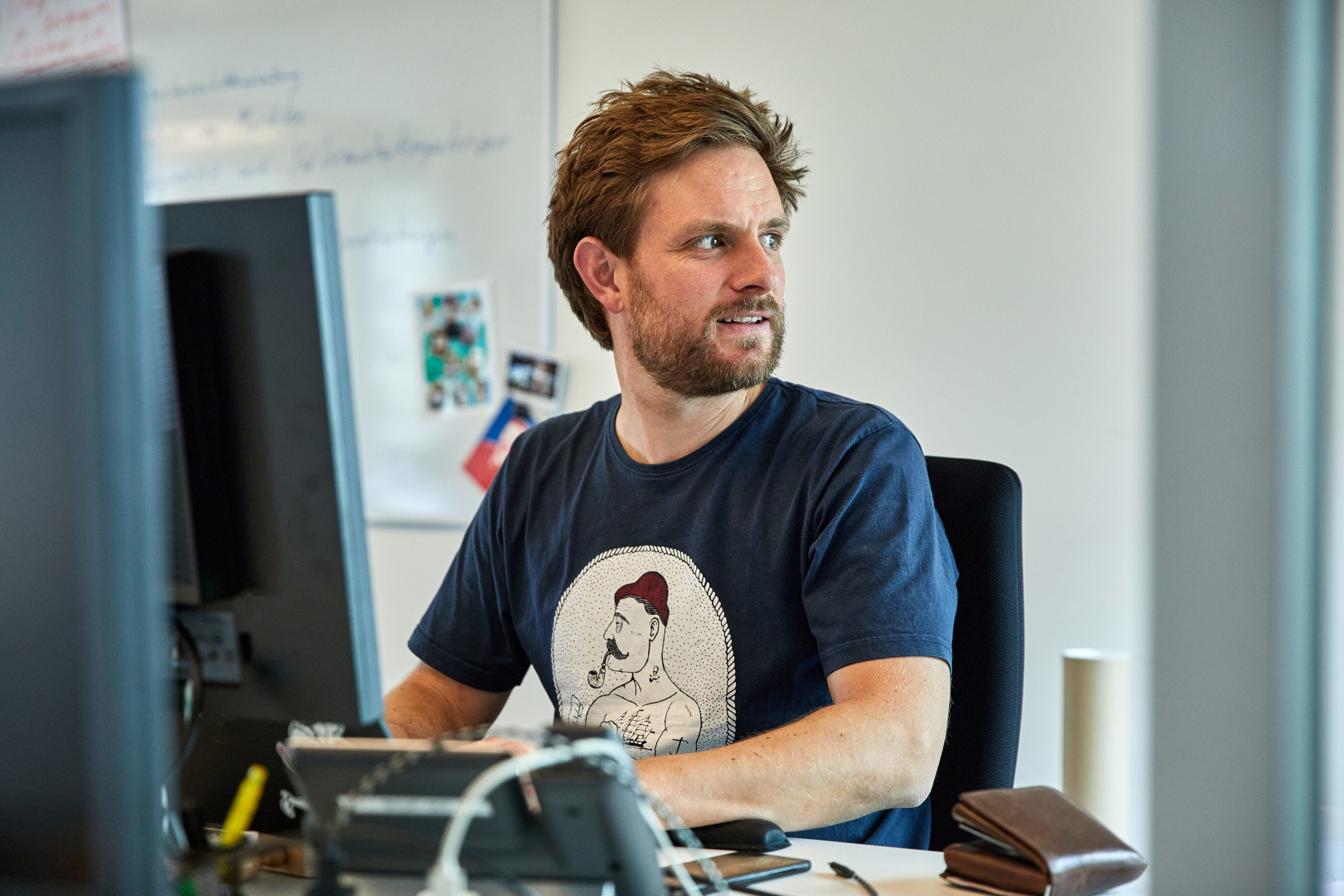 Eine Person sitzt in einem Büro am Computer und schaut zur Seite